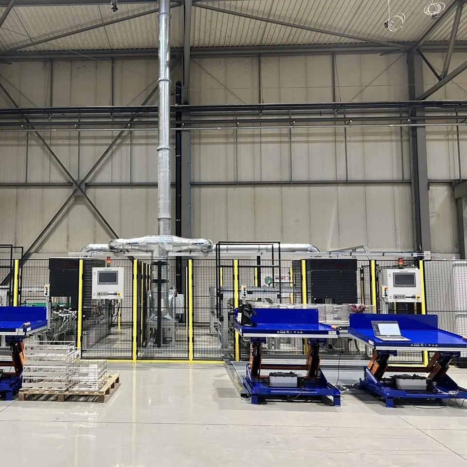 Oil dipping system with four blue lift tables, safety enclosure and operator terminals in the customer's hall.
